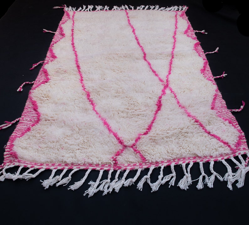 May include: White shag rug with a pink geometric pattern and white fringe.