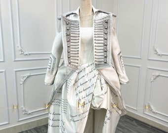 May include: A white jacket with silver buttons and trim, and a white skirt with black script writing. The jacket has a high collar and a fitted silhouette. The skirt is a high-low style, with a longer back hem.