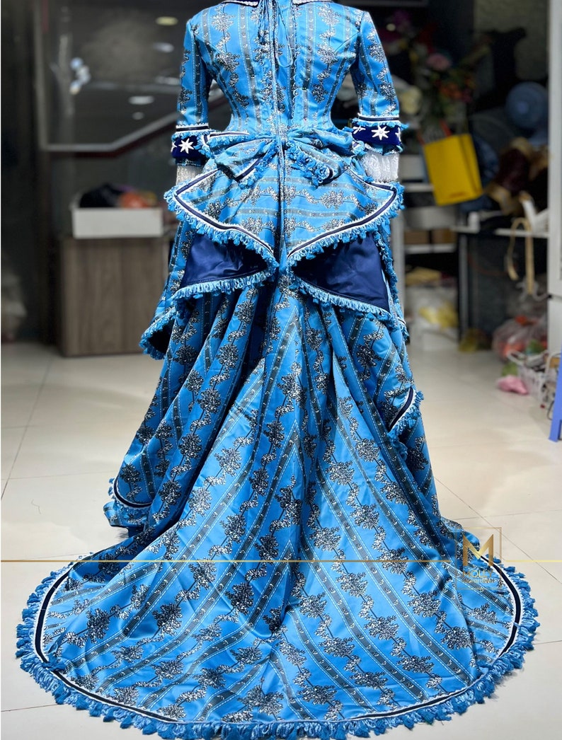 May include: A blue and white patterned dress with a long skirt and a fitted bodice. The dress has a white lace trim and a blue sash. The skirt is full and flowing, and the dress is perfect for a special occasion.