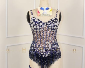 May include: A blue and white sequined bodysuit with a star and moon design. The bodysuit has a fringe trim and a matching garter belt.