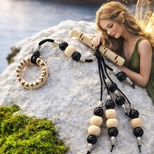 May include: A wooden pendant with a circular design and engraved runes, connected to a beaded strand with black and cream-colored beads. A wooden flute is also present. The items are displayed on a rock surface.