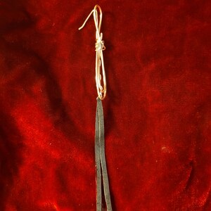 May include: A pair of long, black leather earrings with a silver wire knot at the top.
