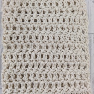 K&ouml;nnte beinhalten: Cremefarbener H&auml;kelstoff mit offenem Gewebe. Die Textur ist sichtbar, mit einem sich wiederholenden Muster aus Knoten und Zwischenr&auml;umen. Der Stoff wirkt weich und geschmeidig, geeignet f&uuml;r verschiedene Bastelprojekte oder Wohnaccessoires. Die neutrale Farbe macht ihn vielseitig.