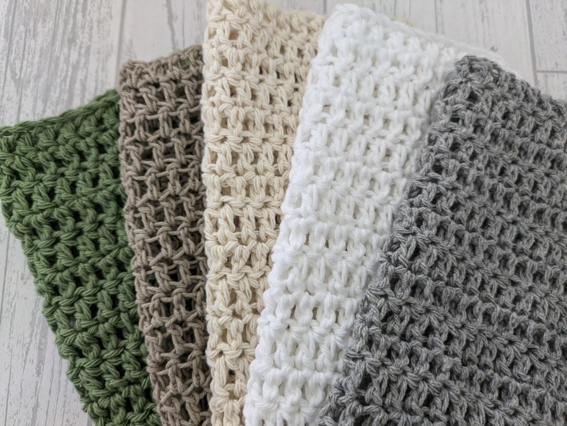 K&ouml;nnte beinhalten: Eine Sammlung von f&uuml;nf geh&auml;kelten Waschlappen in verschiedenen Farben: Gr&uuml;n, Braun, Beige, Wei&szlig; und Grau. Die Waschlappen sind nebeneinander angeordnet und zeigen ihr strukturiertes, offenes Webdesign. Die weichen, neutralen Farbt&ouml;ne erzeugen eine beruhigende &Auml;sthetik.