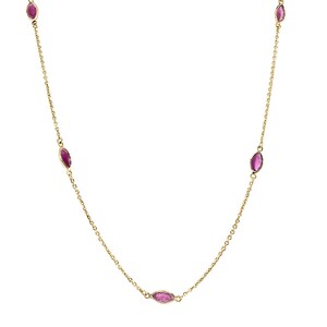 May include: A delicate gold-tone necklace featuring oval-shaped, magenta-colored gemstones spaced along the chain. The necklace is displayed against a white background, highlighting the jewelry's design and color.