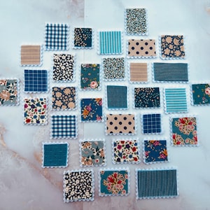 May include: A collection of fabric squares with various patterns and colours, including blue, white, and floral designs. The squares are arranged in a heart shape on a white background.