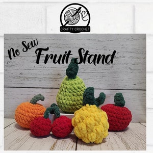 Könnte beinhalten: Häkelmuster für einen Obststand ohne Nähen. Gehäkeltes Obst umfasst eine Birne, zwei Äpfel, einen Kürbis und eine Ananas. Das Obst ist aus Garn in den Farben Grün, Rot, Orange und Gelb gefertigt.