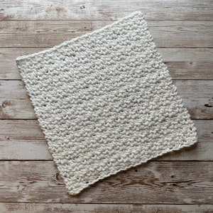 May include: White crocheted dishcloth or kitchen scrubber on a wood background.
