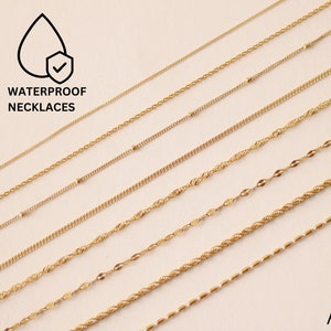 May include: A collection of gold-toned chain necklaces, all laid out in a row on a white background. The text "WATERPROOF NECKLACES" is at the top of the image. The text "AMICA JEWELS" is at the bottom of the image.