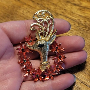 May include: Gold tone reindeer brooch with red and green enamel poinsettia wreath.