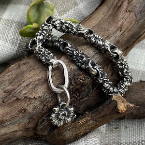 Peut inclure: Un bracelet en argent avec un motif floral. La chaîne est composée de petits maillons en forme de fleurs interconnectés. Le bracelet a un fermoir simple de forme ovale et un petit charme en forme de fleur.