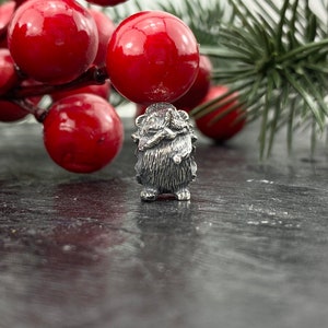 Peut inclure: Une figurine en argent d'un hérisson avec une surface texturée détaillée. La figurine est debout sur une surface gris foncé.