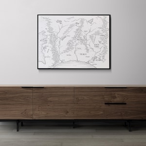 K&ouml;nnte beinhalten: Ein Schwarzwei&szlig;-Kartendruck einer fiktiven Welt mit dem Titel "The Old World" und den Namen verschiedener Regionen, darunter "The Wilds" und "The Aetrith Plains". Die Karte ist in einem schwarzen Rahmen gerahmt und h&auml;ngt an einer wei&szlig;en Wand &uuml;ber einem Holzkasten.