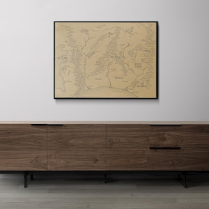 K&ouml;nnte beinhalten: Eine gerahmte Karte der fiktiven Welt von Westeros aus der beliebten TV-Serie Game of Thrones. Die Karte ist in schwarzer Tinte auf beigefarbenem Hintergrund gezeichnet und enth&auml;lt die Namen verschiedener Orte, wie z. B. die Mauer, der Norden und die Flusslande.