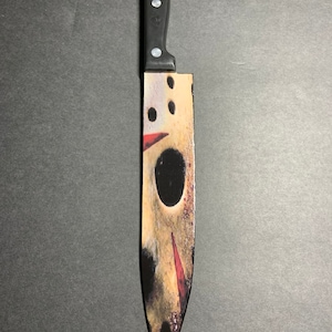 May include: A black-handled kitchen knife with a white and red design featuring a hockey mask on the blade.