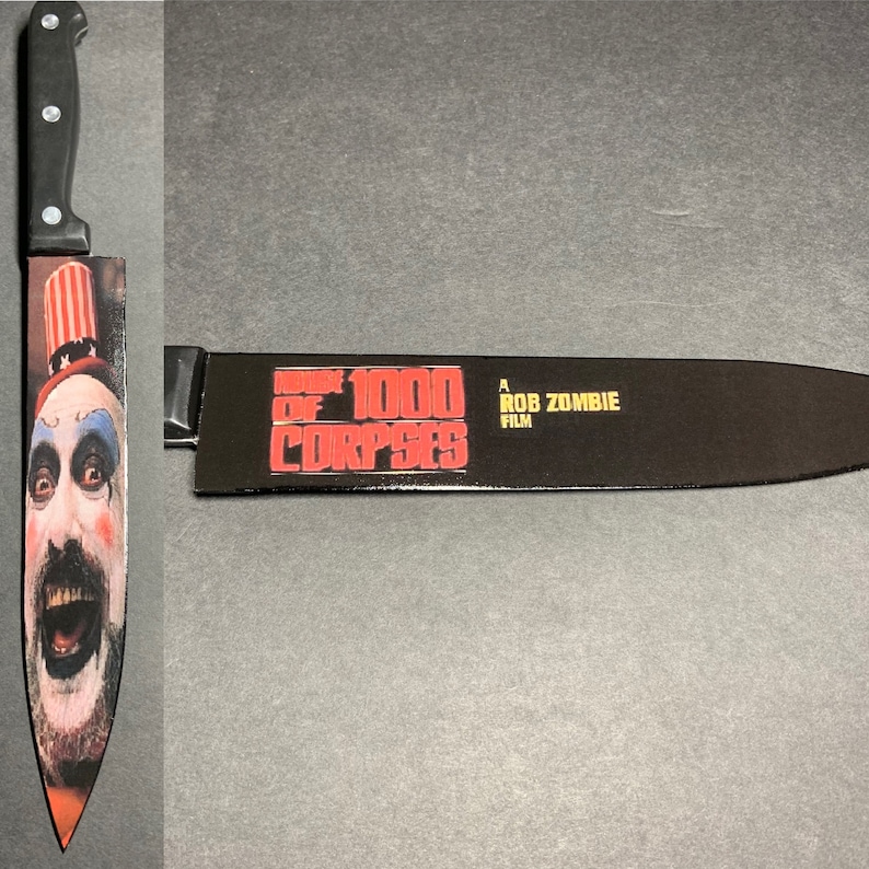 Puede incluir: Un cuchillo de cocina negro con un sombrero de rayas rojas y blancas y una cara de payaso en la hoja. La hoja tambi&eacute;n tiene el texto "House of 1000 Corpses A Rob Zombie Film" impreso en ella.