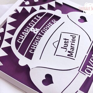 K&ouml;nnte beinhalten: Eine wei&szlig;e, ausgeschnittene Karte mit einem violetten Hintergrund. Die Karte zeigt ein Auto mit den Worten "Charlotte & Christopher" und "Just Married". Das Datum "01/01/20" ist ebenfalls auf der Karte.