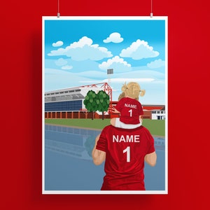 May include: A father and daughter wearing red soccer jerseys with the number "1" on the back, standing in front of a soccer stadium. The daughter is sitting on the father's shoulders. The sky is blue with white clouds.