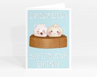 May include: A light blue greeting card with a cartoon illustration of two dim sum dumplings in a bamboo steamer. The text "Dim Sum Body Say It's Your Birthday" is printed on the card.