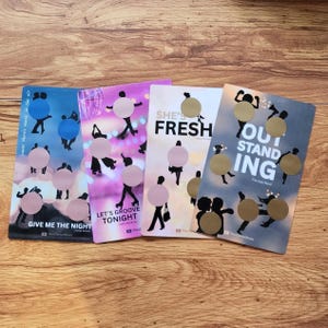 May include: Four colorful cards with a dance theme. Each card features silhouettes of people dancing, with gold circles and text like "Give Me The Night" and "She's Fresh". The cards are on a wooden surface.
