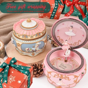 Puede incluir: Una caja de música rosa y azul con temática de carrusel con una figura de bailarina. La caja está decorada con detalles dorados y un diseño de caballo de carrusel. La tapa está abierta, revelando una figura de bailarina.