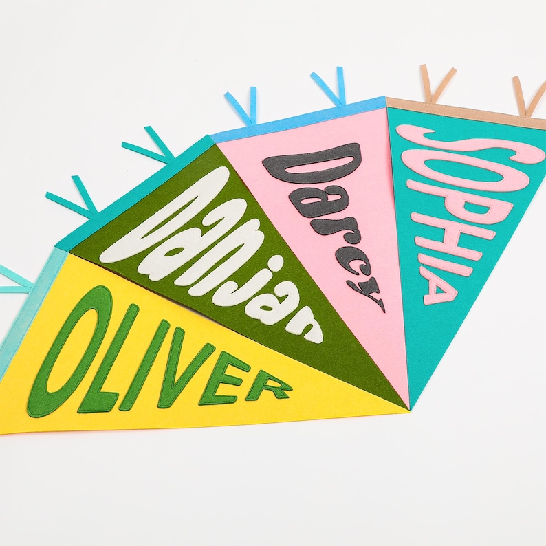 K&ouml;nnte beinhalten: Ein farbenfroher Filz-Wimpelbanner mit den Namen Oliver, Danjan, Darcy und Sophia in einer Retro-Schrift. Die Wimpel sind gelb, gr&uuml;n, rosa und blau.