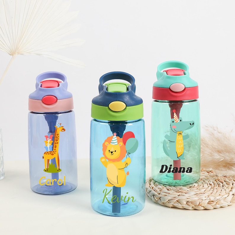 Pu&ograve; includere: Tre bottiglie d'acqua riutilizzabili colorate con coperchi a cannuccia e nomi personalizzati: Carol, Kevin e Diana. Ogni bottiglia presenta una grafica di un animale diverso: una giraffa, un leone e un alligatore.