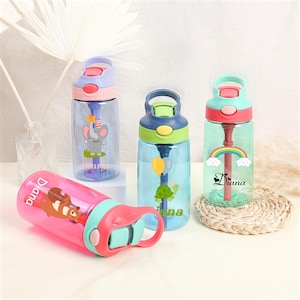 Pu&ograve; includere: Quattro bottiglie d'acqua riutilizzabili colorate con coperchi a cannuccia e nomi personalizzati. Le bottiglie sono blu, verdi, rosa e viola con vari disegni di animali dei cartoni animati.