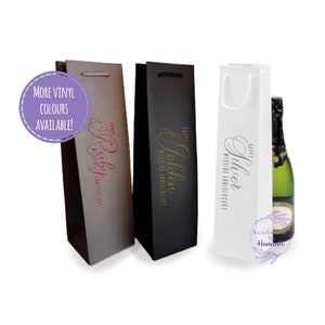 May include: Three wine gift bags with different coloured backgrounds and gold lettering. The bags are labelled "Happy Ruby Wedding Anniversary", "Happy Golden Wedding Anniversary", and "Happy Silver Wedding Anniversary".