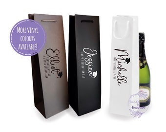 May include: Three personalized wine gift bags with black and white text. The bags are gray, black, and white. The text on the bags reads "Elliot", "Jessica", and "Michelle". The bags are decorated with a graduation cap icon. The text on the bags also reads "Congratulations on your graduation" and "Happy Graduation Day".