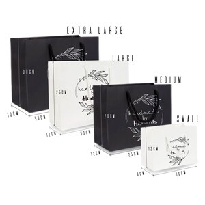 Peut inclure: Quatre sacs cadeaux de diff&eacute;rentes tailles en noir et blanc avec des poign&eacute;es. Les sacs sont &eacute;tiquet&eacute;s "Extra Large", "Large", "Medium" et "Small". Chaque sac a un design noir et blanc avec le texte "handmade by Hannah" et un motif floral.