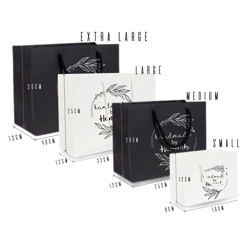 Peut inclure: Quatre sacs cadeaux de diff&eacute;rentes tailles en noir et blanc avec des poign&eacute;es. Les sacs sont &eacute;tiquet&eacute;s "Extra Large", "Large", "Medium" et "Small". Chaque sac a un design noir et blanc avec le texte "handmade by Hannah" et un motif floral.