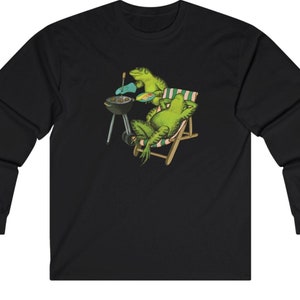 Op de afbeelding: Een zwart longsleeve t-shirt met een afbeelding van twee groene leguanen die barbecueën op een houtskoolgrill. Eén leguaan zit in een gestreepte strandstoel.