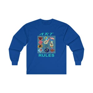 Pu&ograve; includere: Una t-shirt a maniche lunghe blu reale con un design grafico di materiali artistici colorati e il testo "ART RULES" in turchese.