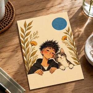 Pu&ograve; includere: Una stampa artistica rettangolare con un'illustrazione in stile cartoon di una persona dai capelli scuri con una felpa nera, accanto a un gatto tigrato. La scena presenta steli floreali gialli su entrambi i lati e un cerchio blu.