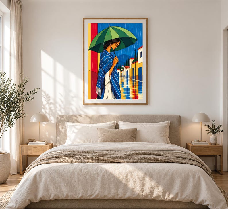 May include: A framed wall art print depicting a person standing in the rain under a large green umbrella. The person wears a blue and white striped shawl over a white garment. The background shows a street with colorful buildings.