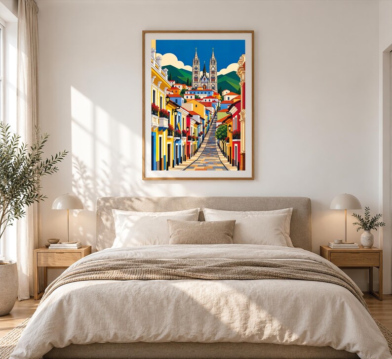 May include: A framed vertical art print featuring a vibrant street scene with colorful buildings leading toward a large cathedral under a bright blue sky with white clouds, set against a backdrop of green mountains and rolling hills.