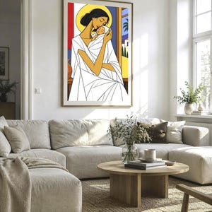 May include: A framed wall art print featuring a stylized illustration of a person with dark hair and a yellow halo holding a swaddled infant. The figure wears a white garment with geometric lines, set against a background of red, blue, and yellow.