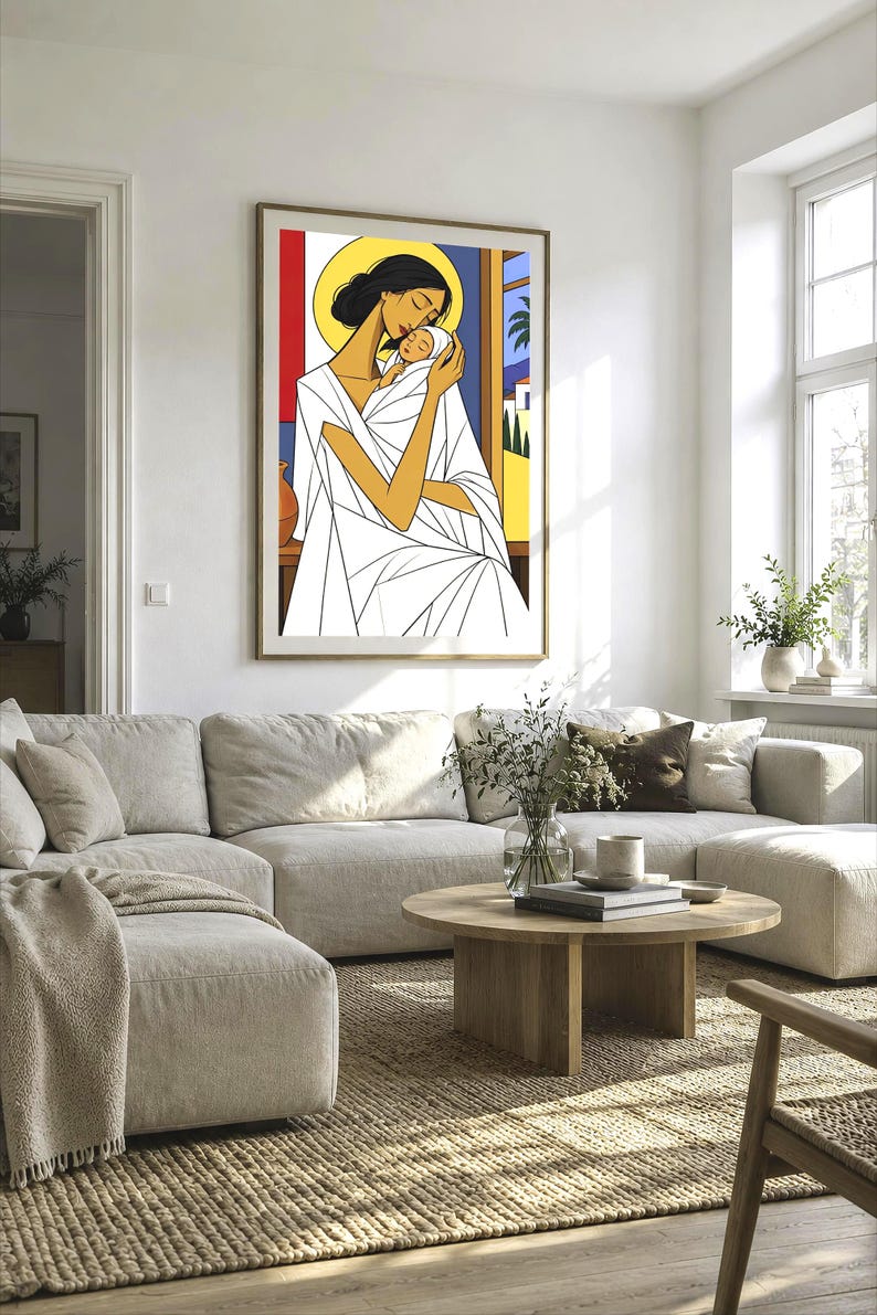 May include: A framed wall art print featuring a stylized illustration of a person with dark hair and a yellow halo holding a swaddled infant. The figure wears a white garment with geometric lines, set against a background of red, blue, and yellow.