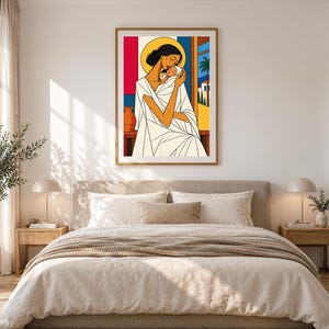 May include: A framed wall art print featuring a stylized illustration of a person with dark hair holding a baby. The figure wears a white garment with geometric folds. A yellow halo surrounds the head, set against a background of red, blue, and a landscape with a palm tree.