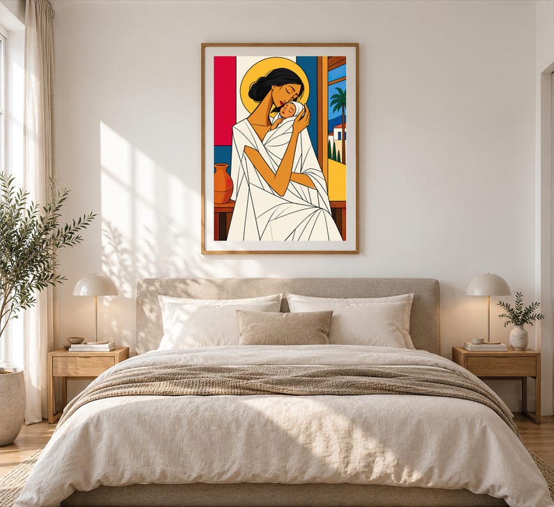 May include: A framed wall art print featuring a stylized illustration of a person with dark hair holding a baby. The figure wears a white garment with geometric folds. A yellow halo surrounds the head, set against a background of red, blue, and a landscape with a palm tree.