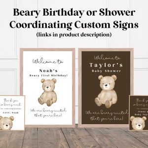 Może przedstawiać: Skoordynowane niestandardowe znaki na baby shower lub urodziny. Znaki zawierają ilustrację misia i tekst "Witamy na pierwszym urodzinach Noah!" oraz "Witamy na baby shower Taylor".