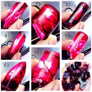 May include: A collection of eight rough, red ruby gemstones. The gemstones are various shapes and sizes. Some of the gemstones are in a hand, while others are on a black surface.