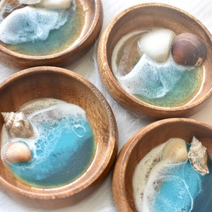Könnte beinhalten: Vier kleine Holzschalen mit blauem und weißem Harz im Inneren, jede mit Muscheln. Die Schalen eignen sich perfekt zum Aufbewahren von Schmuck oder anderen kleinen Gegenständen.