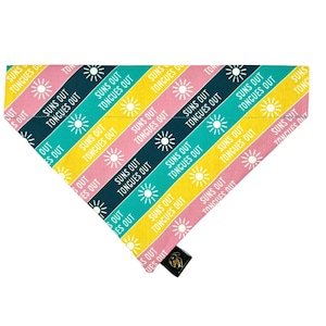 May include: A colourful dog bandana with a repeating pattern of yellow, pink, blue and green stripes. The text "Suns Out Tongues Out" is repeated on the bandana.