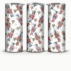 Puede incluir: Tres vasos de acero inoxidable con fondo blanco y un patrón repetido de soldados cascanueces de acuarela y estrellas blancas.