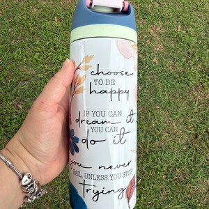 K&ouml;nnte beinhalten: Eine wei&szlig;e Wasserflasche mit blauem, gr&uuml;nem und rosa Deckel. Die Flasche ist mit floralen Designs und den Worten "choose to be happy", "if you can dream it, you can do it" und "you never fail, unless you stop trying" verziert.