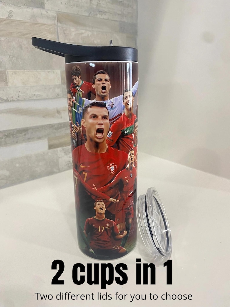 May include: A stainless steel tumbler with a black lid and a colorful image of soccer players on the side. The tumbler has a black handle and the text "2 cups in 1" and "Two different lids for you to choose" are printed below the tumbler.