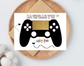 May include: A white card with a black and white illustration of a video game controller. The card has the text "TU ES ADMISSIBLE À UN NOUVEAU JEU, GRATTE POUR CONNAITRE LE TITRE" and "SURPRISE!" in rainbow colors.