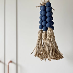 May include: A dark blue beaded tassel with a natural jute tassel. The beads are strung on a natural twine cord.